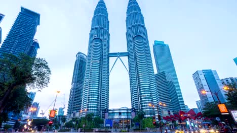 De-la-noche-al-día,-HD-time-lapse-de-la-intersección-semáforo-en-frente-de-Suria-KLCC-con-torres-Petronas.