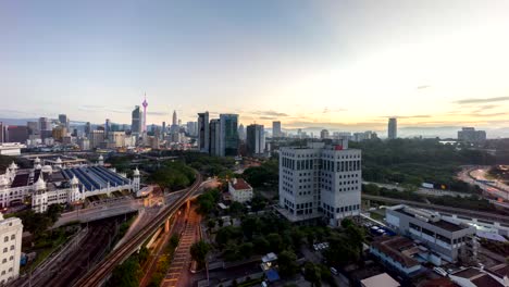 timelapse-of-beautiful-sunrise-at-Kuala-Lumpur-city-centre-from-a-rooftop-of-a-building,-with-city-skyline,-train,-and-burst-sunlight.