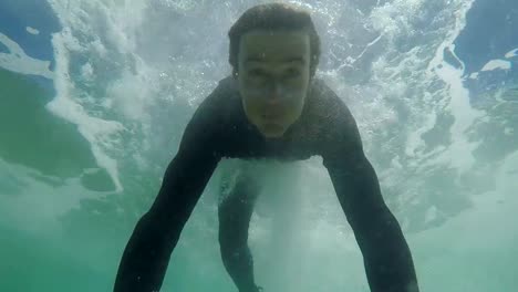 MOVIMIENTO-SLOW-CLOSE-UP:-Feliz-joven-surfista-haciendo-pato-buceo