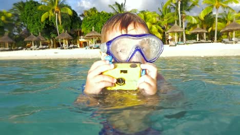 Child-bathing-in-ocean-and-taking-photos-with-waterproof-camera