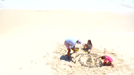 Blick-von-oben-auf-Vater-und-Töchter-machen-Sandburg-am-tropischen-Strand