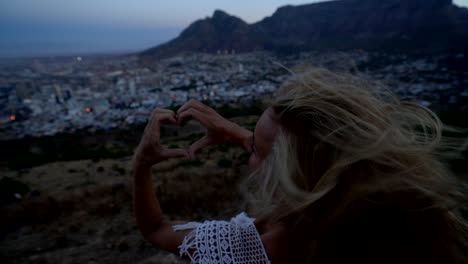 Mujer-joven-haciendo-forma-marco-de-corazón-en-ciudad-del-cabo-al-amanecer