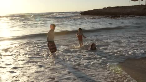 Drei-Kinder-spielen-am-Strand-zusammen