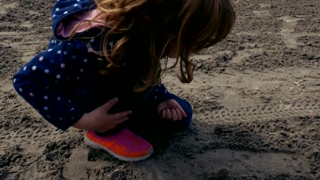 Chica-jugando-con-la-arena-húmeda