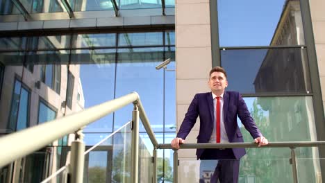 Businessman-is-leaning-on-railing-near-building.