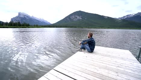 Young-male-on-lake-pier-looking-at-view