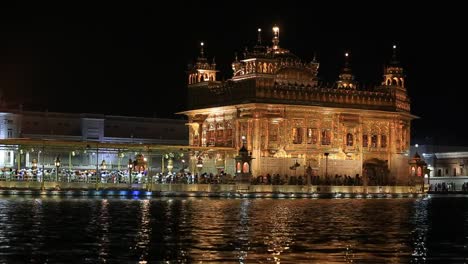 Sikhs-y-gente-India-visitando-el-templo-dorado-en-Amritsar,-en-la-noche.-India