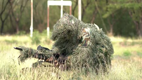 Sniper-soldier-lying-on-the-ground-and-camouflage-in-grass.-Soldier-holding-gun-weapon-and-waring-armor-uniform.-The-military-is-responsible-for-maintaining-the-territory.