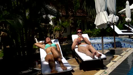 Women-sunbathing-in-bathing-suits-on-a-sun-lounger.-Woman-drinking-a-cocktail