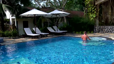 Man-swims-in-the-pool.-Man-swims-up-to-the-stairs-and-out-of-the-pool