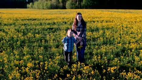 Mutter-und-Sohn-gehen-auf-dem-Gebiet-der-gelben-Blüten.