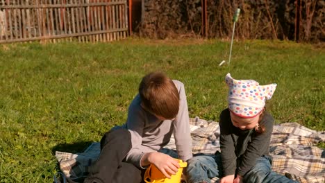 Bruder-und-Schwester-anzeigen-Regenwürmer-sitzen-auf-dem-Rasen-im-Garten-des-Hauses.