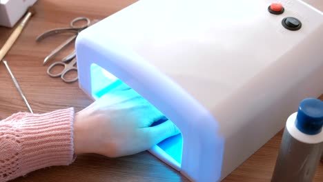 Woman-dries-her-nails-with-shellac-in-UV-lamp.-Close-up.