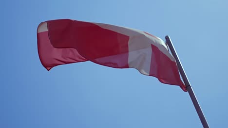 Bandera-de-Dinamarca-ondeando-en-el-viento-con-cielo-azul