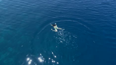 Aerial-Footage-of-a-Girl-Swimming-In-Blue-Sea