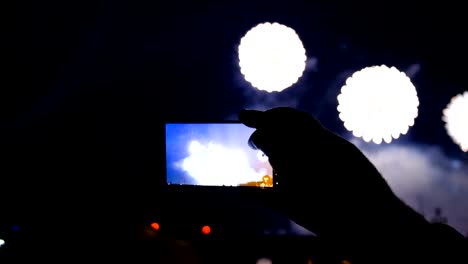 Man-shoots-fireworks-on-the-phone-and-watches-salute-through-the-smartphone-screen