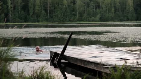 Caucasian-mature-man-jumping-from-wooden-pier-in-lake.