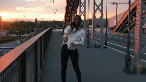 Young-Woman-Dancing-on-City-Bridge-and-Golden-Sunset-Panorama