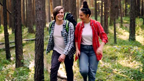 Handsome-young-man-is-hiking-with-his-friend-cheerful-young-woman-talking-and-laughing-touching-trees-and-enjoying-nature-and-conversation.-Friends-and-hike-concept.