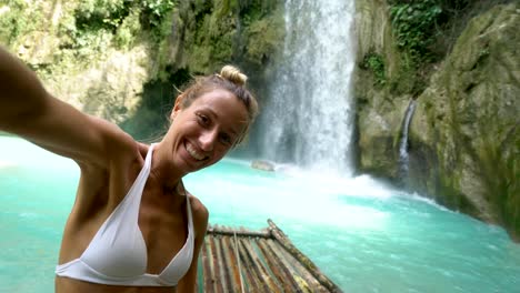 Junge-Frau-unter-Selfie-Porträt-mit-einem-wunderschönen-Wasserfall-auf-der-Insel-Cebu-in-den-Philippinen.-Die-Leute-reisen-Natur-Selfie-Konzept.-Eine-Person,-die-nur-genießen,-Natur-und-Ruhe-in-einem-friedlichen-Umfeld---4K-video