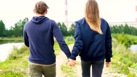 Un-hombre-joven-y-una-chica-están-caminando-por-el-sendero-junto-al-río.