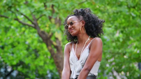 Moda-joven-negro-vestido-con-gafas-de-sol-redondas-y-camisola-divirtiéndose-y-riendo-al-aire-libre,-primer-plano