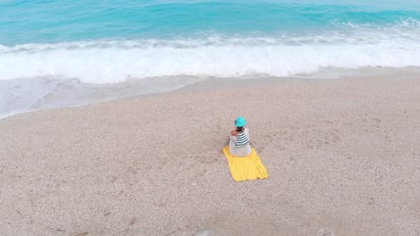 Frau-am-Strand-sitzen-und-welliges-Meer-beobachten