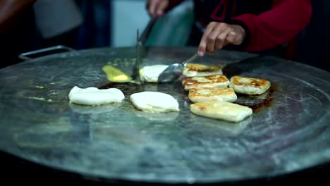 Vendedor-de-comida-callejera-haciendo-Roti-Canai-en-una-sartén