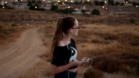 Teenage-girl-with-eyeglasses-listening-to-the-music-on-sunset