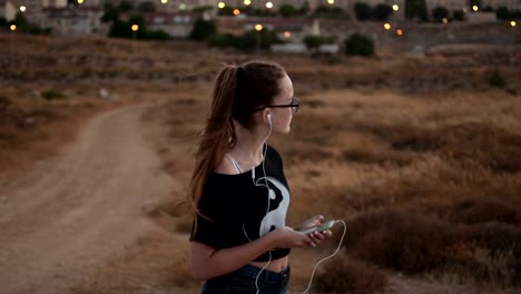 Teenager-Mädchen-mit-eyeglasses-hören-Sie-die-Musik-auf-den-Sonnenuntergang