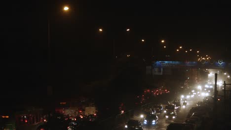 Fade-in-shot-of-traffic-on-road-in-a-city-at-night,-Delhi,-India