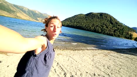 Cheerful-young-woman-takes-a-selfie-portrait-by-the-lake