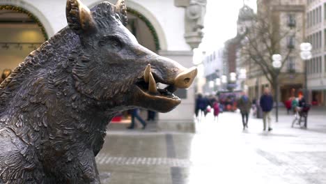 Bronze-statue-of-wild-boar-in-historical-city-center,-tourists-walking-around