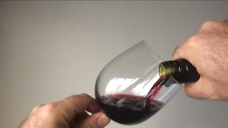 Slow-Motion-eines-Mannes-Rotwein-aus-der-Flasche-in-ein-Glas-Wein-in-Strömen