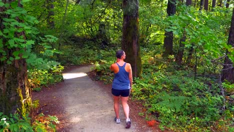 Cáncer-optimista-sobreviviente-mujer,-caminando-por-sendero-de-grava-abajo-bosque