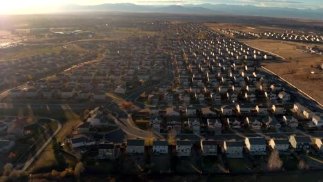 ANTENA:-Ciudad-suburbana-grande-con-hileras-de-casas-rodeado-de-montañas-al-amanecer