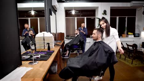 In-a-fashionable-barber-shop-there-is-a-haircut-of-several-visitors,-men-are-waiting-for-the-end-of-their-haircuts-and-hair-styling-with-the-help-of-gel-and-other-styling