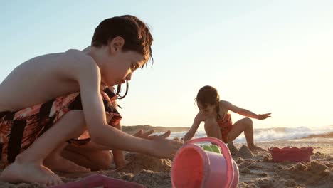 Tres-niños-jugando-en-la-playa-construyendo-castillos-de-arena-juntos