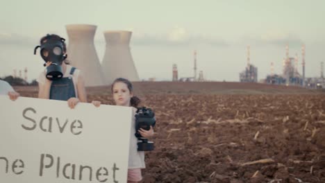 Save-the-plant.-Young-kids-holding-signs-near-a-refinery-with-gas-masks