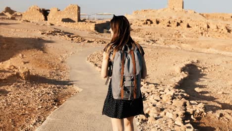 Frau-mit-Rucksack-erkundet-Wüste-Ruinen.-Schöne-europäische-touristische-Spaziergänge-auf-Felsen-und-Sand.-Masada-Israel-4K