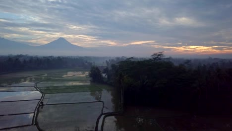 Aerial-view-drone-shot-of-Borobudur-town-in-Java-at-sunrise,-Indonesia-Travel-religion-drone-concept-4K-resolution-Rice-fields-and-volcano