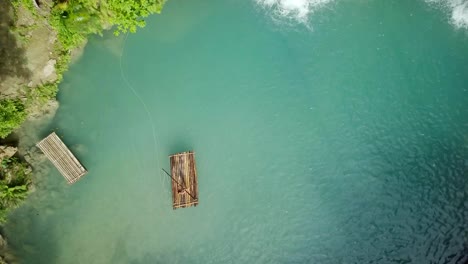 Drone-shot-aerial-view-of-young-woman-bamboo-rafting-at-tropical-waterfall.-4K-resolution-video,-shot-in-the-Philippines.-People-travel-fun-vacations-adventure-concept