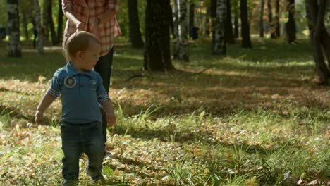 Beautiful-young-mother-and-her-adorable-toddler-son-having-fun-together-in-autumn-park,-boy-is-running-from-his-mommy