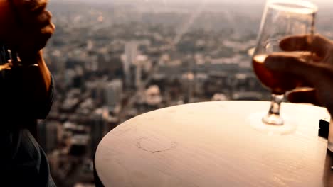 Close-up-view-of-two-cocktails-standing-on-the-table-in-restaurant-in-skyscraper.-Man-and-woman-on-a-romantic-date