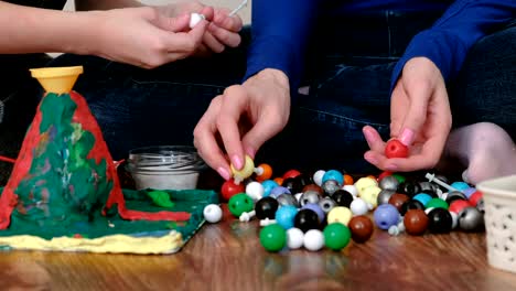 Closeup-hands-of-mom-and-son-building-molecule-models-of-colored-plastic-construction-set.