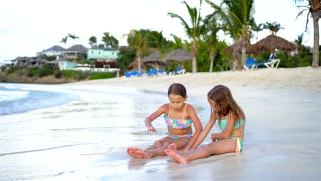 Entzückende-kleine-Mädchen-spielen-mit-Sand-am-Strand