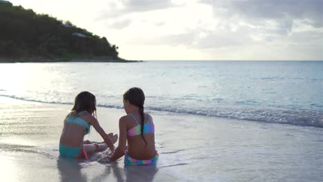 Entzückende-kleine-Mädchen-spielen-mit-Sand-am-Strand