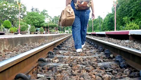 Frauen-tragen-Jeans-mit-Gepäck-auf-ein-Bahngleis.-Sie-stolpern,-aber-noch-geht-nach-vorne.-Konzeption,-Reisen,-Kampf-für-harte-Arbeit