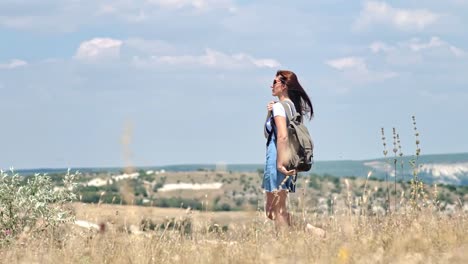 Niedrigen-Winkel-weibliche-Touristen-tragen-Rucksack-und-eine-Sonnenbrille,-die-zu-Fuß-unterwegs-im-Bereich-getrocknetes-Gras