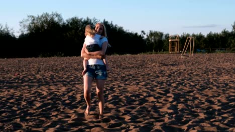 Mother-and-daughter-on-the-beach.-Mother-spinning-with-her-daughter-in-her-arms.